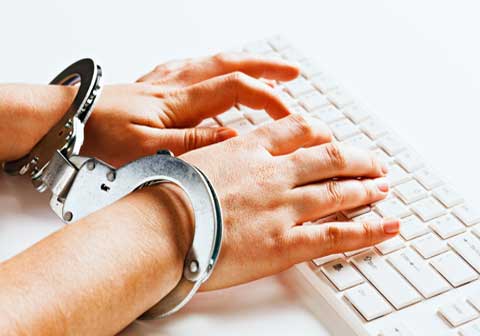 Person typing on keyboard with handcuffs